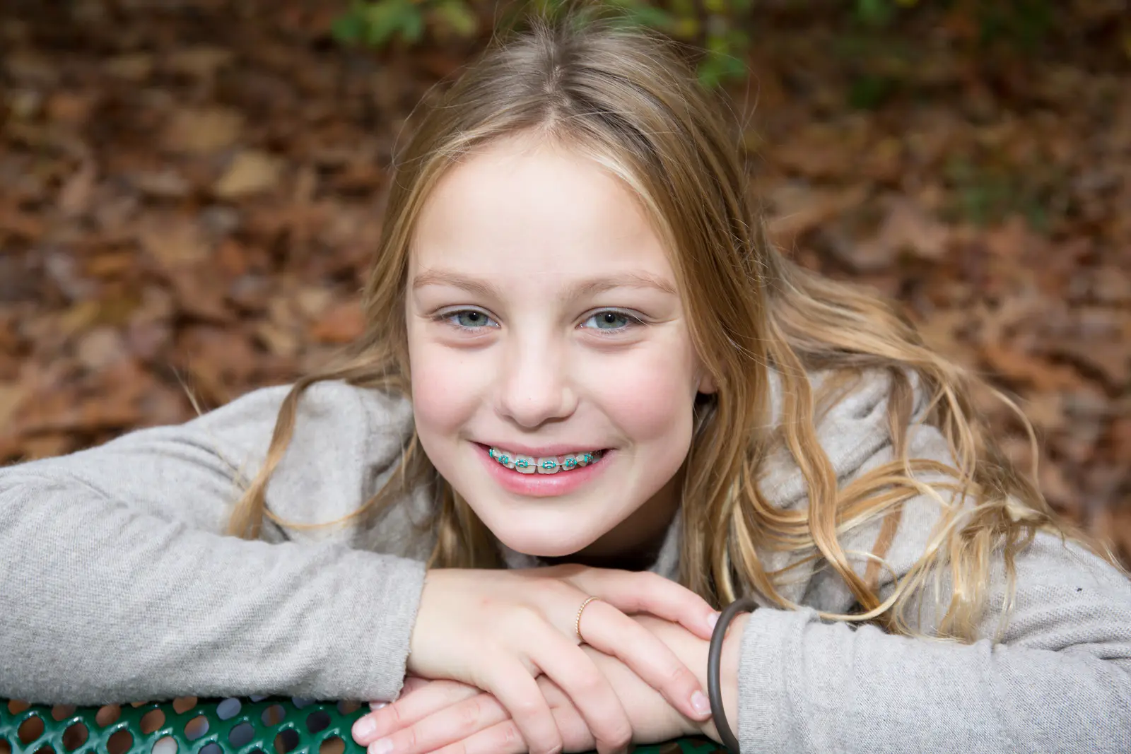 Girl outside looking at camera, smiling, wearing braces