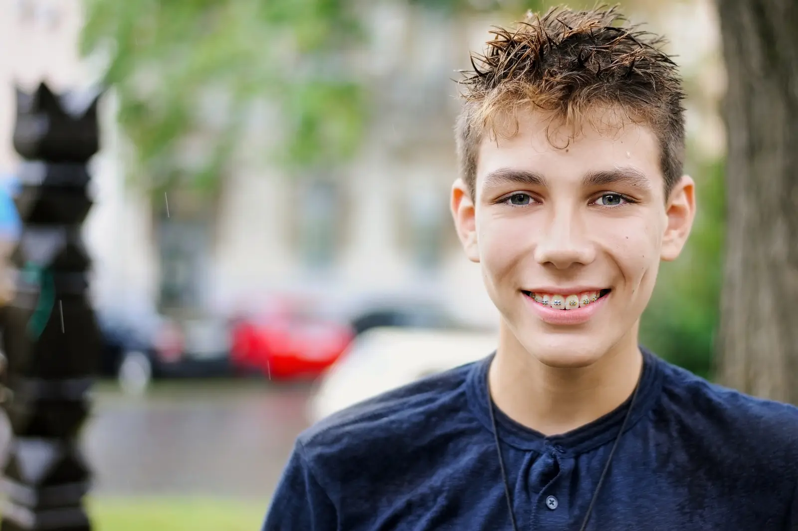 Young male smiling at camera outside wearing braces